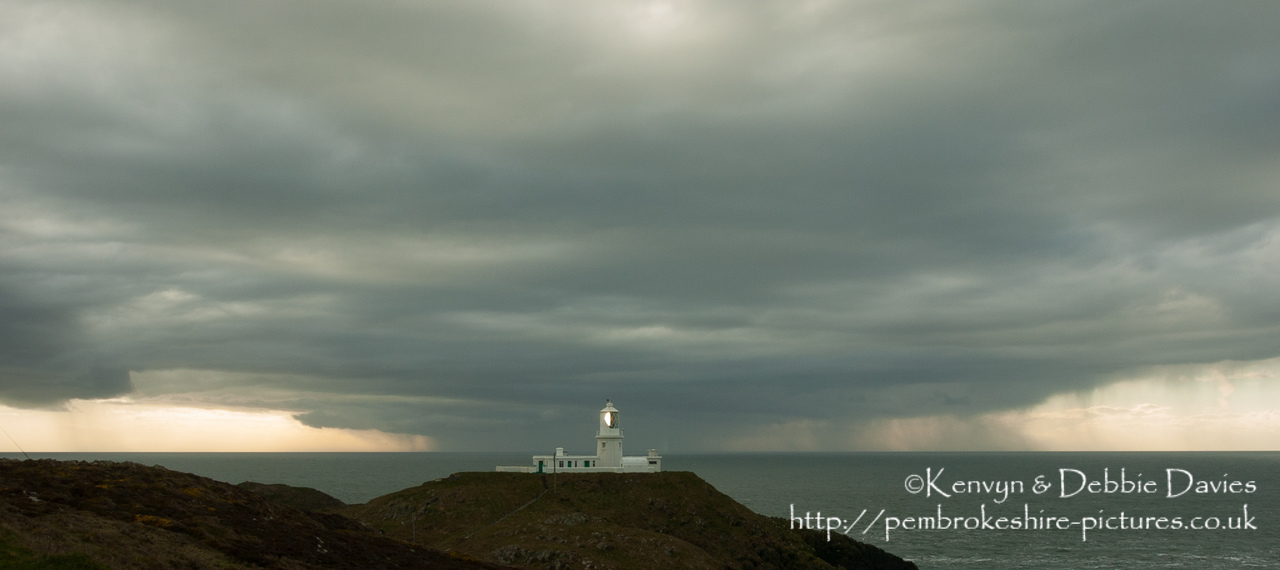 Strumble Head Lighthouse is built on Ynysmeicl (St. Michael's Island), an islet to the west of Fishguard, separated from the mainland by a very narrow gap.<br/><br/>The station was built in 1908 by Trinity House for the greater safety of sea traffic between Ireland and Fishguard Harbour which is located behind cliffs and a breakwater three miles to the east. The new light also formed a link with the existing South Bishop light, 18 miles to the south-west. This stretch of coast is very dangerous, and some 60 vessels are known to have been lost along it in the 19th Century alone.