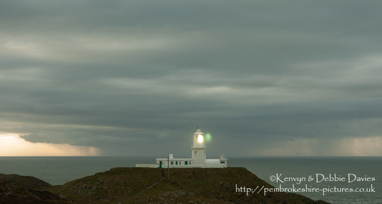 Strumble Head Lighthouse is built on Ynysmeicl (St. Michael's Island), an islet to the west of Fishguard, separated from the mainland by a very narrow gap.<br/><br/>The station was built in 1908 by Trinity House for the greater safety of sea traffic between Ireland and Fishguard Harbour which is located behind cliffs and a breakwater three miles to the east. The new light also formed a link with the existing South Bishop light, 18 miles to the south-west. This stretch of coast is very dangerous, and some 60 vessels are known to have been lost along it in the 19th Century alone.