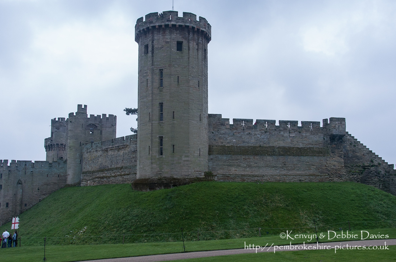 Warwick Castle is a medieval castle developed from an original built by William the Conqueror in 1068. Warwick is the county town of Warwickshire, England, situated on a bend of the River Avon. The original wooden motte-and-bailey castle was rebuilt in stone in the 12th century. During the Hundred Years War, the facade opposite the town was refortified, resulting in one of the most recognisable examples of 14th century military architecture. It was used as a stronghold until the early 17th century, when it was granted to Sir Fulke Greville by James I in 1604. Sir Fulke Greville converted it to a country house. It was owned by the Greville family, who became earls of Warwick in 1759, until 1978 when it was bought by the Tussauds Group.<br/><br/>From Wikipedia ([http://en.wikipedia.org/wiki/Warwick_Castle]).